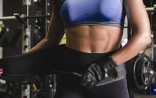 Woman putting on weight lifting belt.