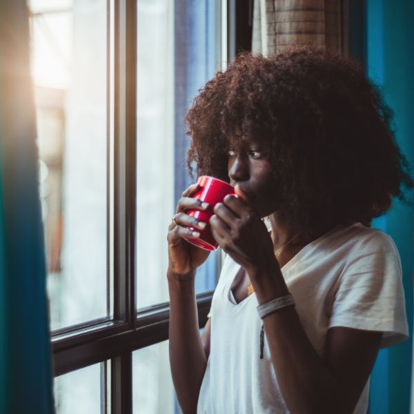 African American woman sipping tea by the window.