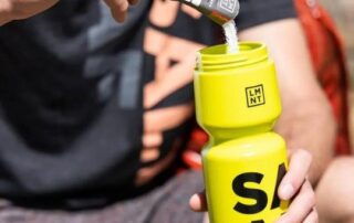 Man adding LMNT electrolytes to his yellow water bottle.