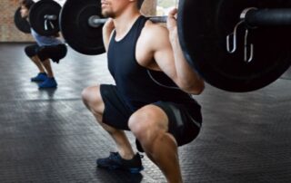 Man performing a weighted barbell back squat.
