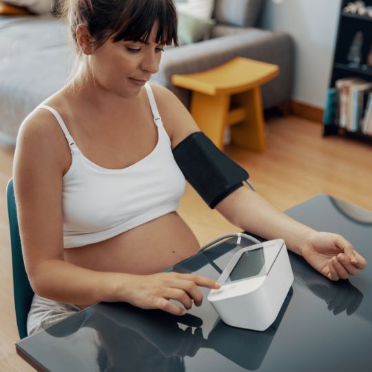 Pregnant woman taking her blood pressure.