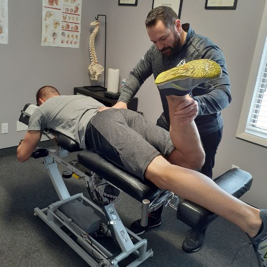 Caucasian male chiropractor working on a caucasian male patient with low back pain.
