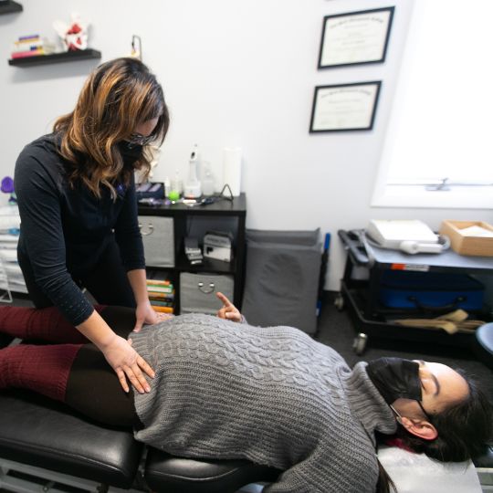 Pregnant female being adjusted by female chiropractor.