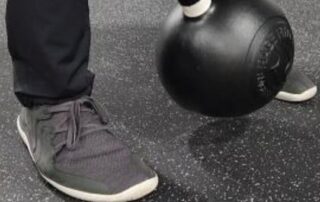 Man performing a kettle bell deadlift while wearing wide toe box shoes.