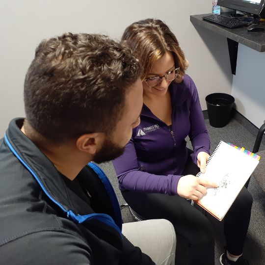 Female chiropractor reviewing intake form with patient.