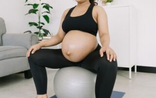 Pregnant asian woman performing an exercise on a balance ball.