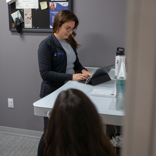 Female chiropractor documents patient records.