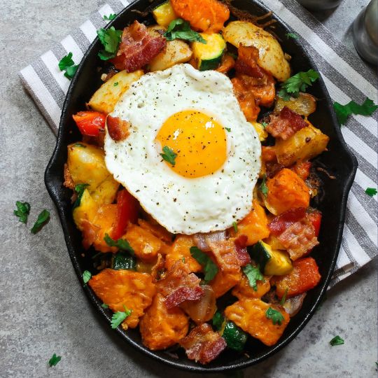 Breatkfast skillet with potatoes, veggies, and a fried egg.