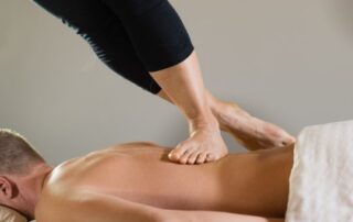 Caucasian man getting an ashiatsu massage from a caucasion woman.