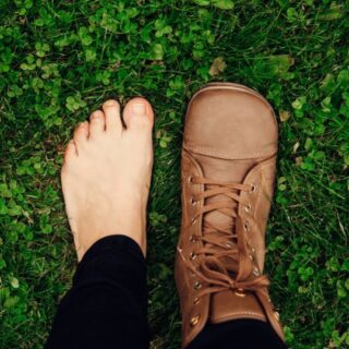 Caucasian person with one bare foot and one foot in a wide toe box barefoot shoe.