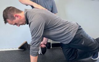 Caucasian male chiropractor assessing caucasian male patient's movement.