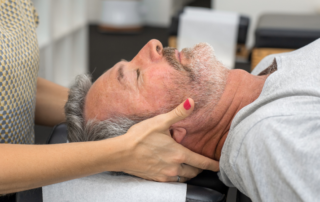 Caucasian senior man getting his neck worked on by a chiropractor.