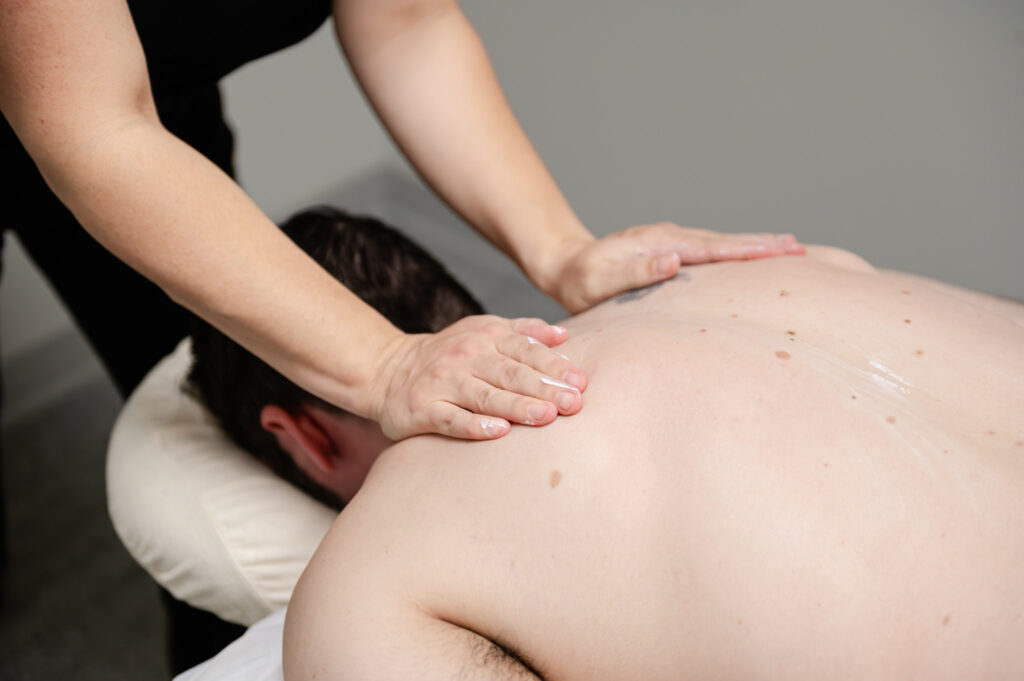 Female massage therapist administering massage on a male client.