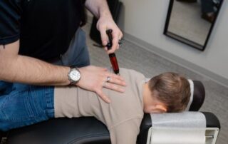 Chiropractor performing spinal adjustment on a child with idiopathic adolescent scoliosis to support scoliosis progression and stabilization.