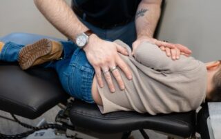 Chiropractor performing a gentle spinal adjustment on an adolescent patient lying on their side.