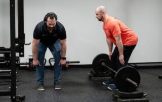 Chiropractor demonstrating proper deadlift form during strength training session